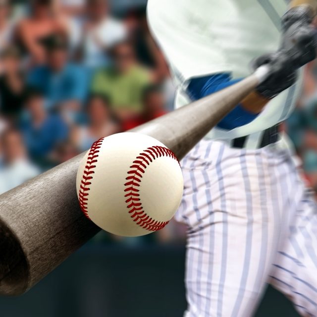 Baseball player hitting ball with bat in close up